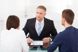 Attorney speaking to a couple and writing on paperwork