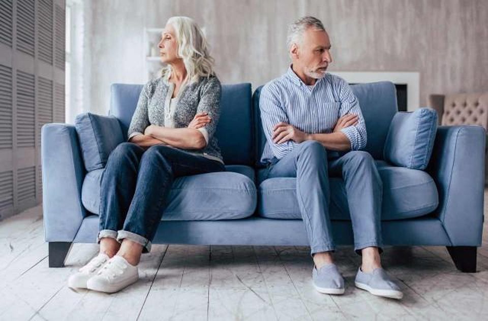 Unhappy older couple sitting on a couch facing away from each other
