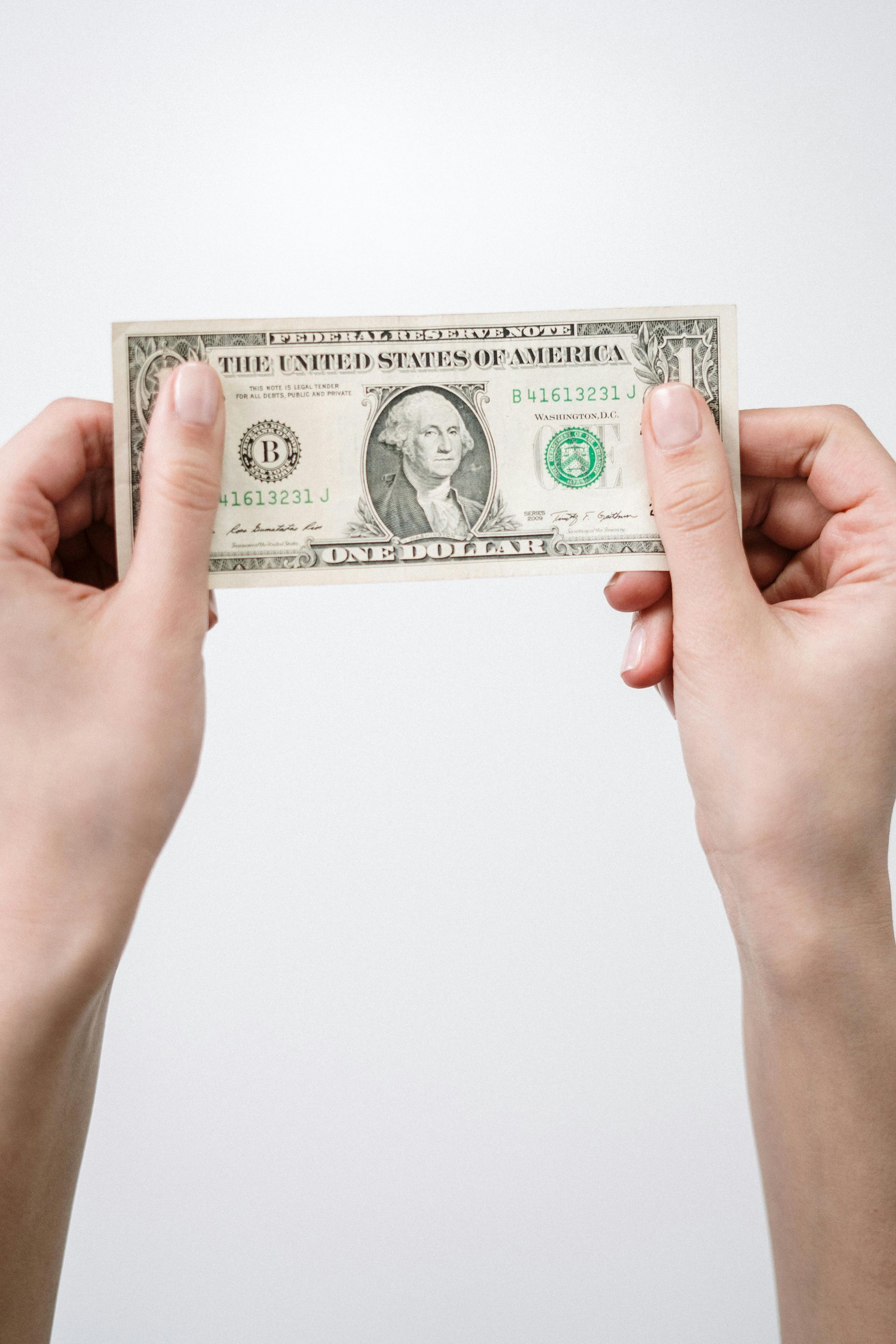 Hands holding a U.S. one-dollar bill against a white background.