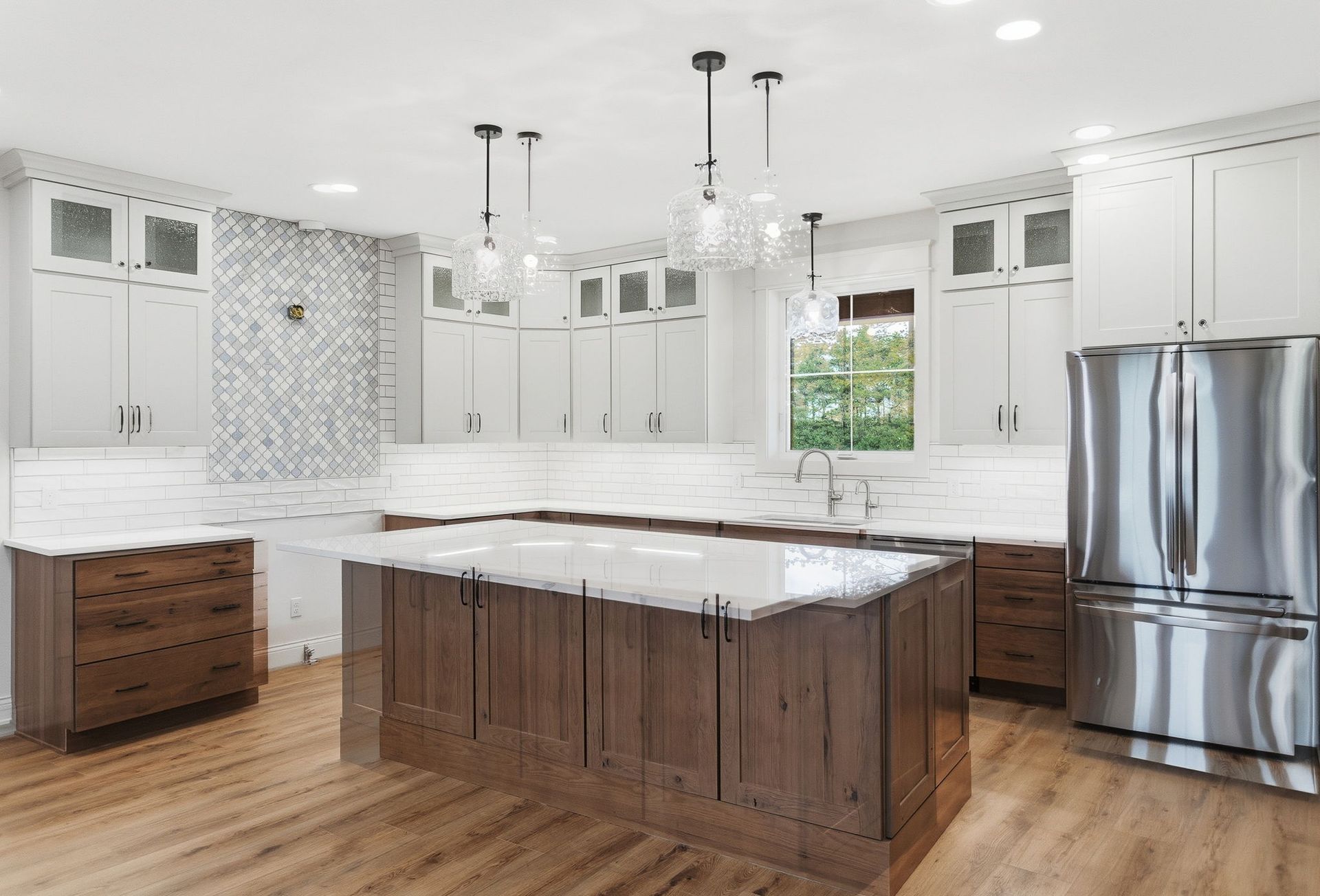 Bright modern kitchen with white cabinets, stainless steel fridge, and wood island