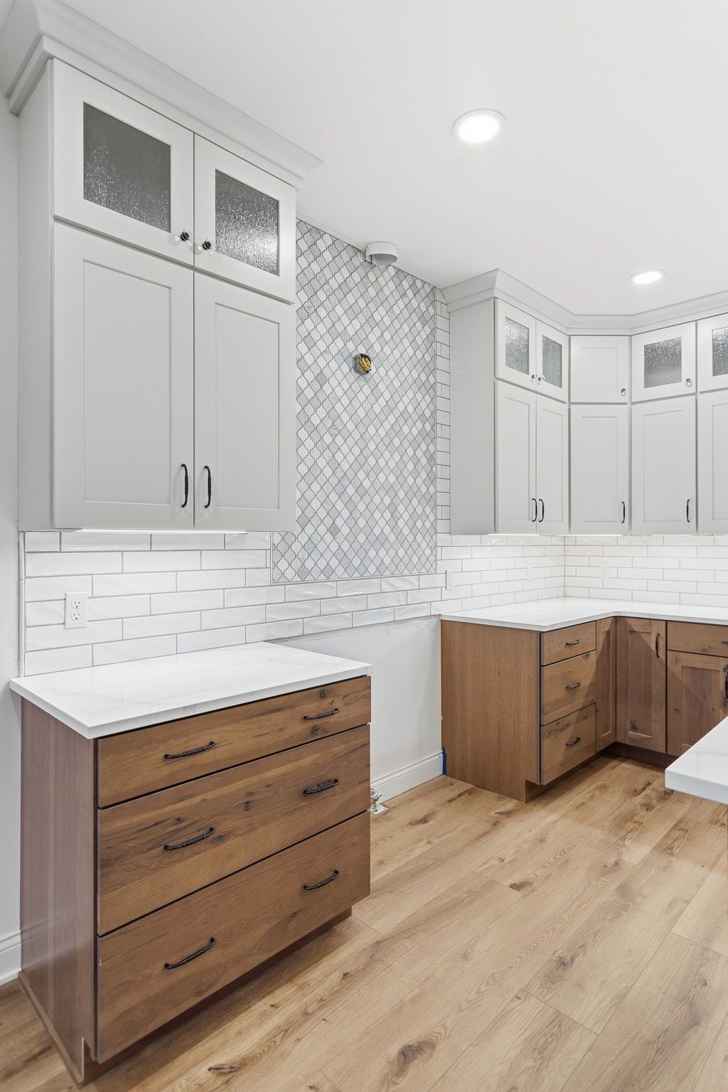 Bright laundry room with white cabinets, wood drawers, and light wood flooring￼