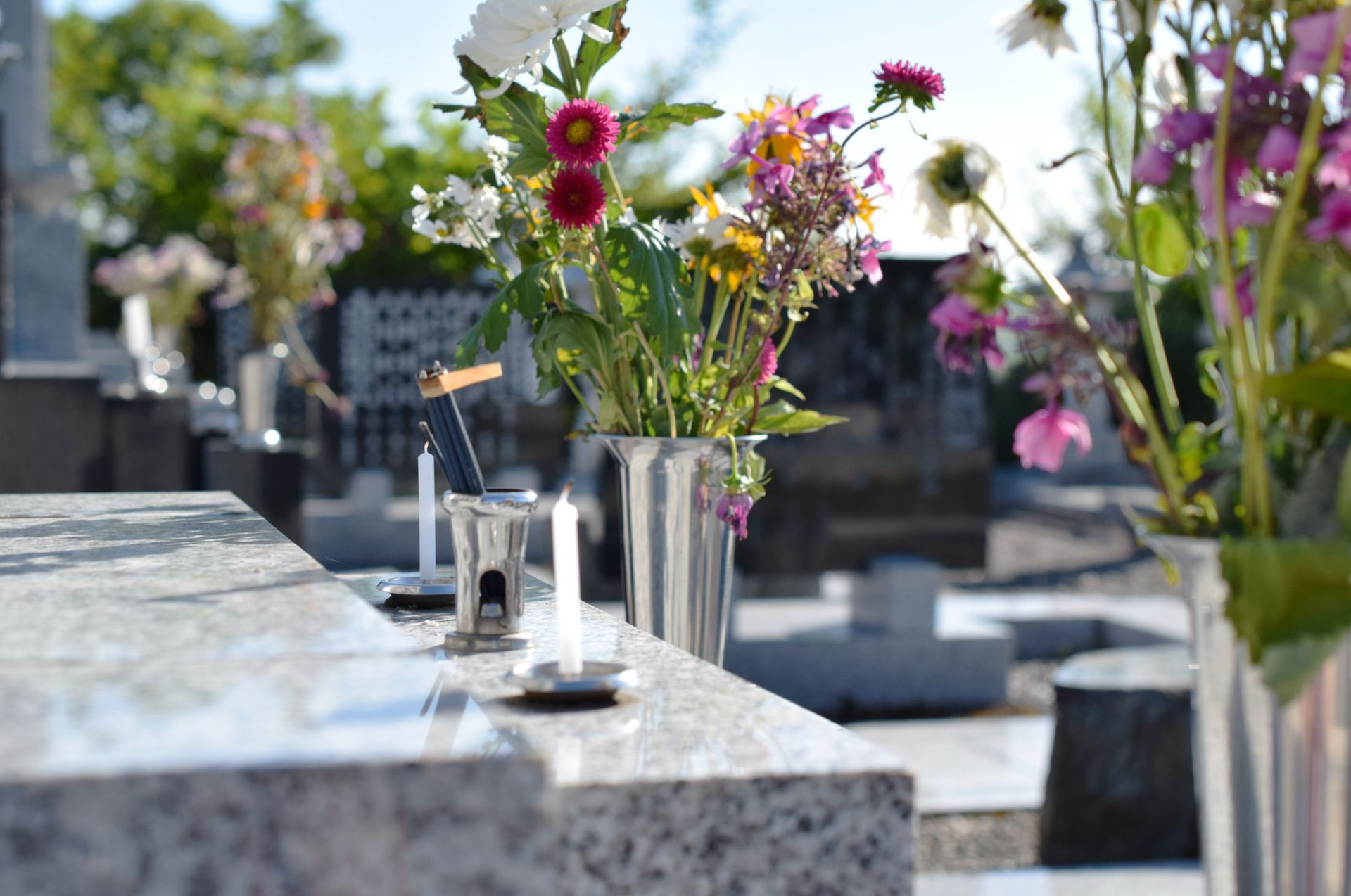 Un cimetière avec des fleurs dans des vases et des bougies sur une tombe.