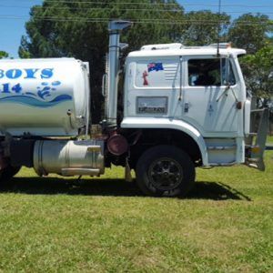 A white tanker truck parked on green grass with a blue and white logo on the tank and an Australian flag on the cab.