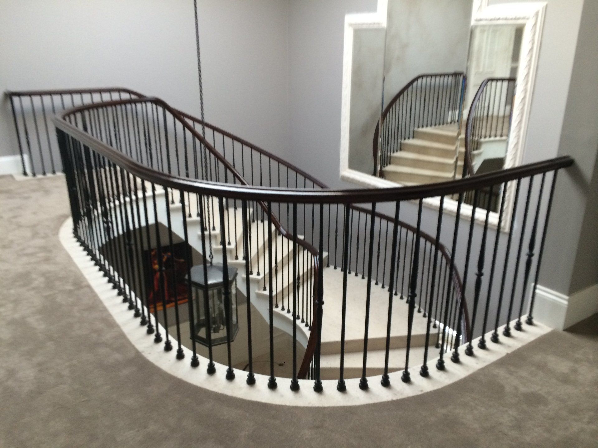 A curved staircase with a black railing and a mirror