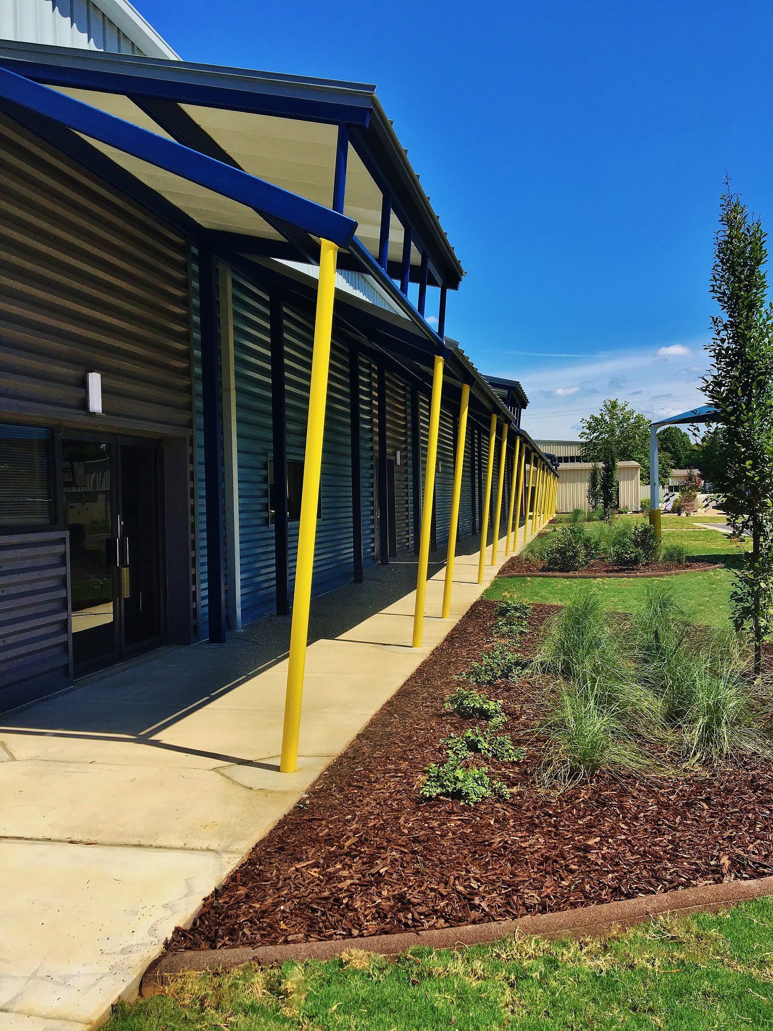 A long walkway leading to a building with a blue roof and yellow poles.