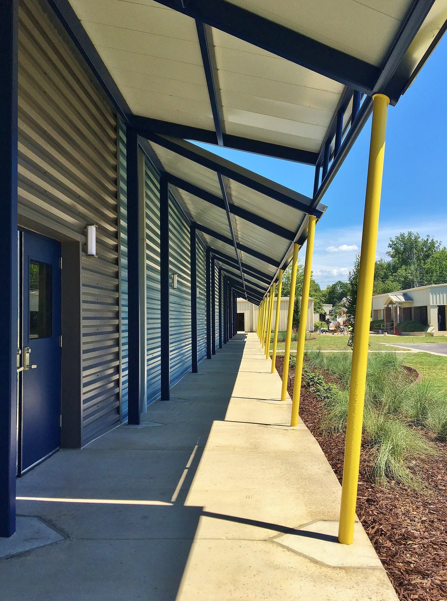 A long walkway leading to a building with a blue door