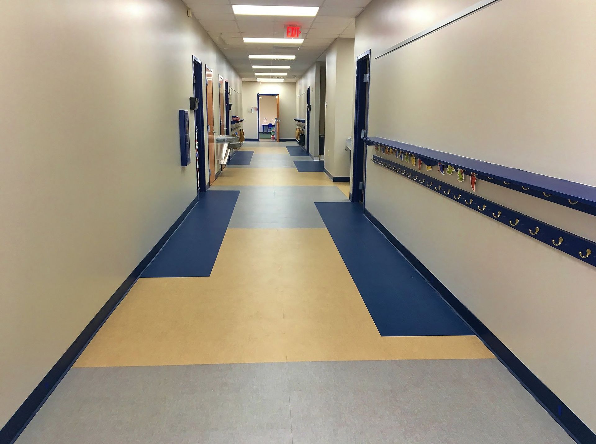 A long hallway with a red exit sign on the wall