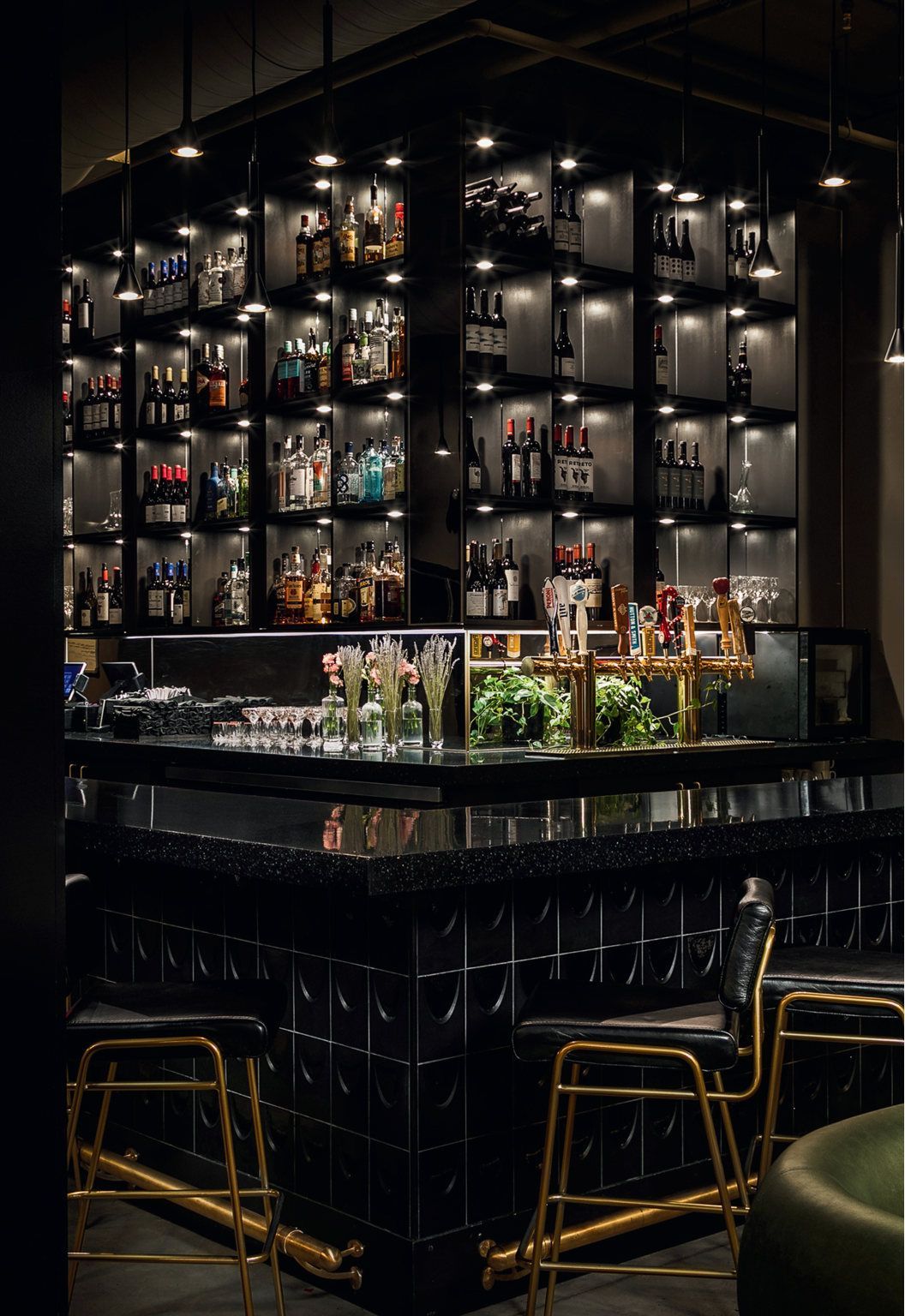 A bar with a lot of bottles on the shelves behind it.