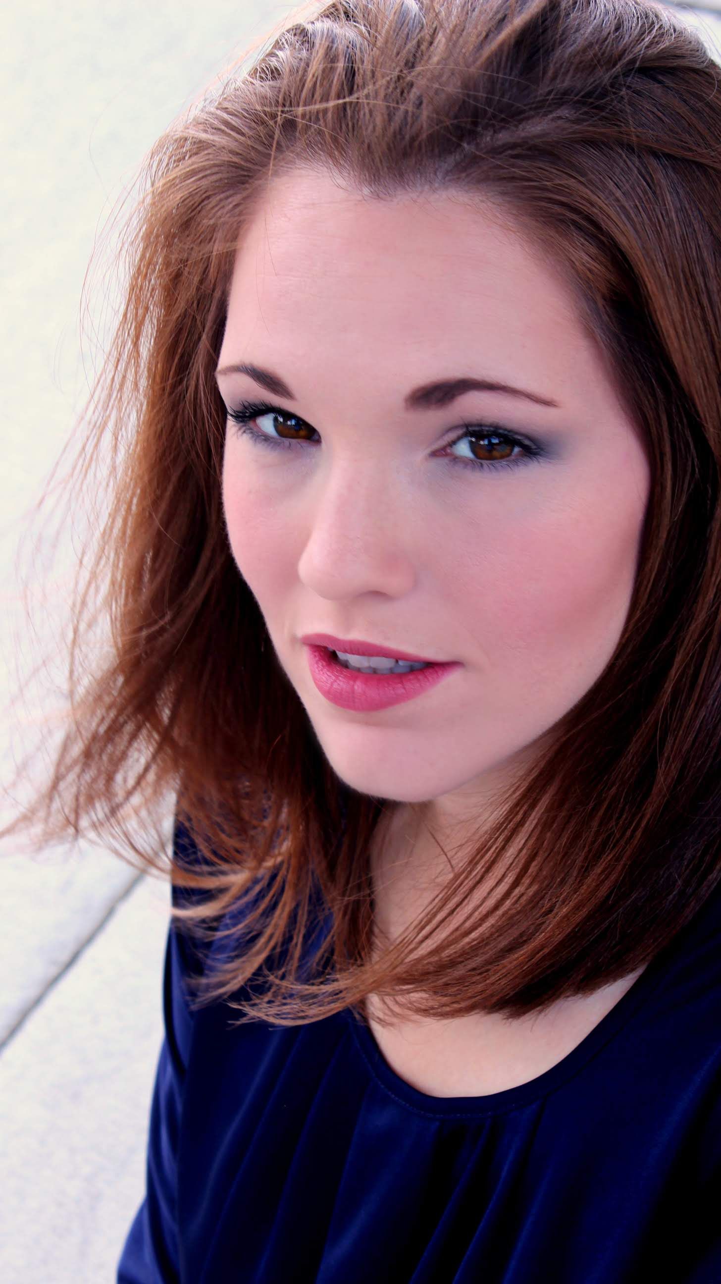 A close up of a woman 's face wearing a blue shirt.