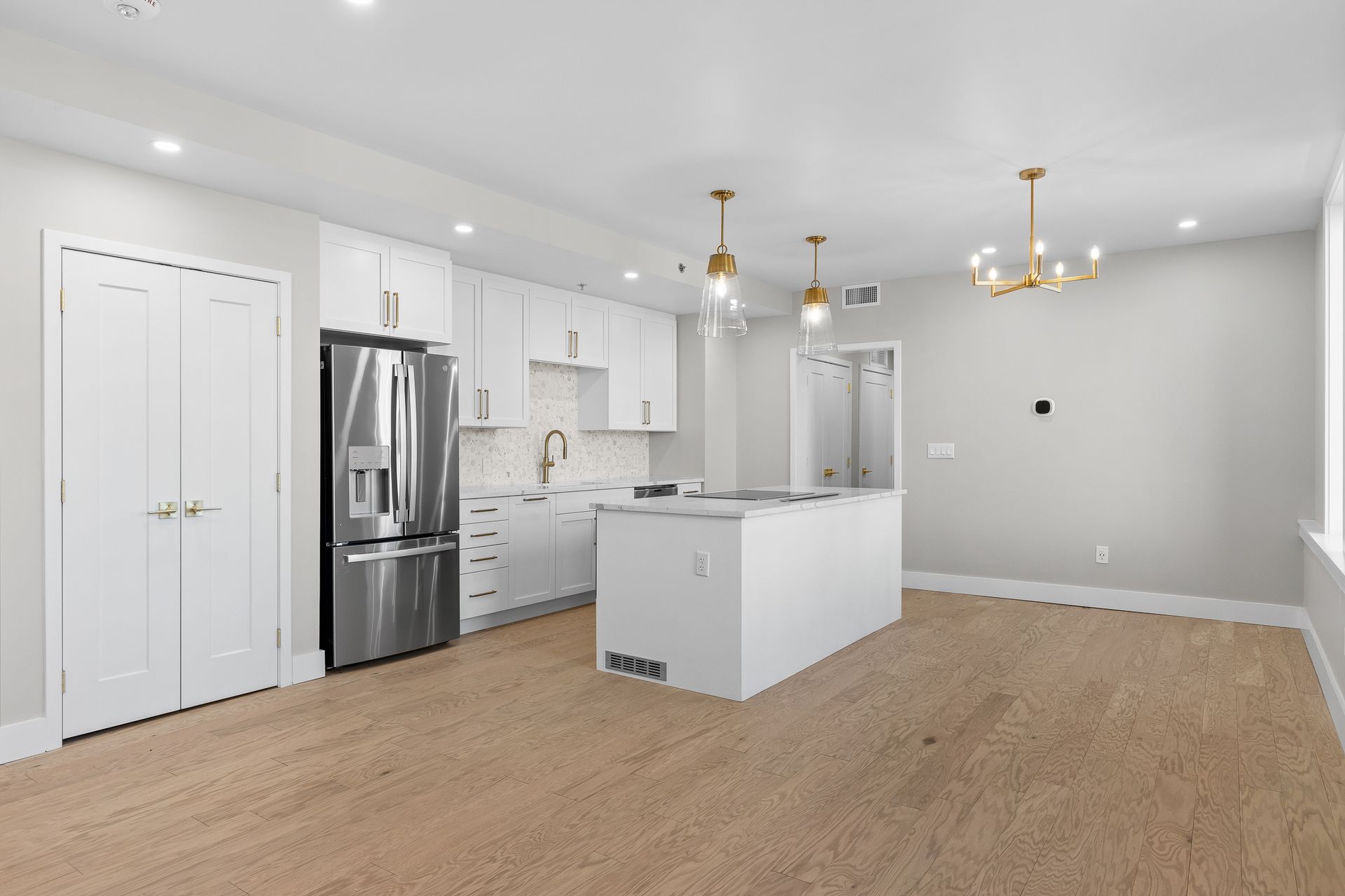 A kitchen with white cabinets , stainless steel appliances , and a large island.