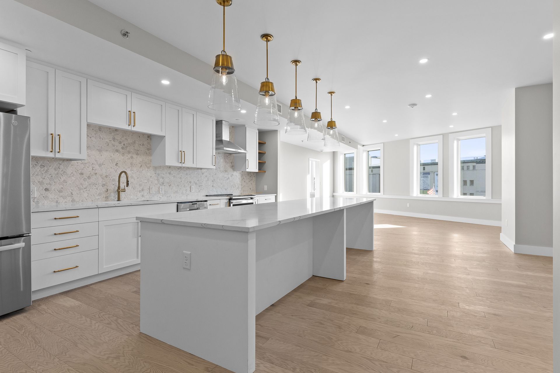 A kitchen with white cabinets , stainless steel appliances , and a large island.