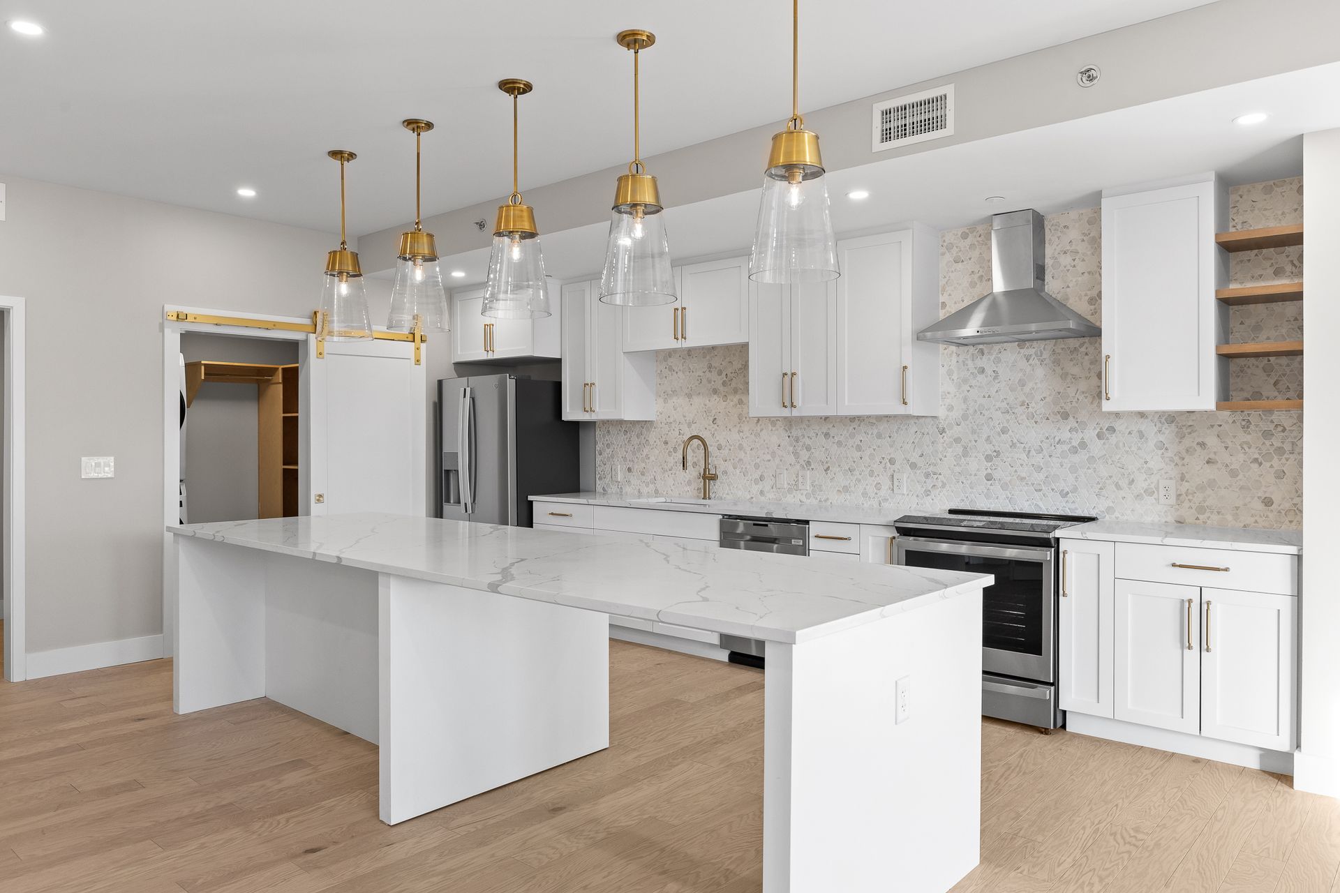 A kitchen with white cabinets , stainless steel appliances , and a large island.