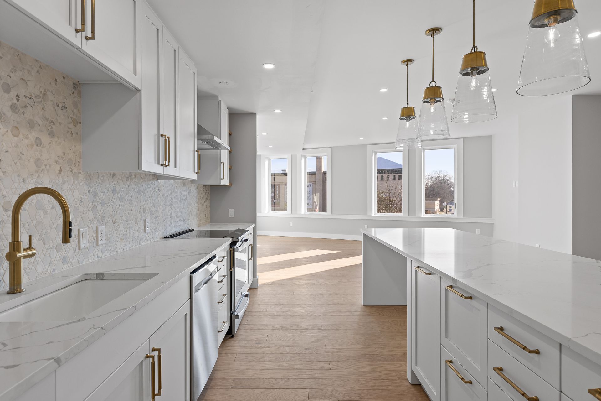 A kitchen with white cabinets , a sink , a stove , and a large island.