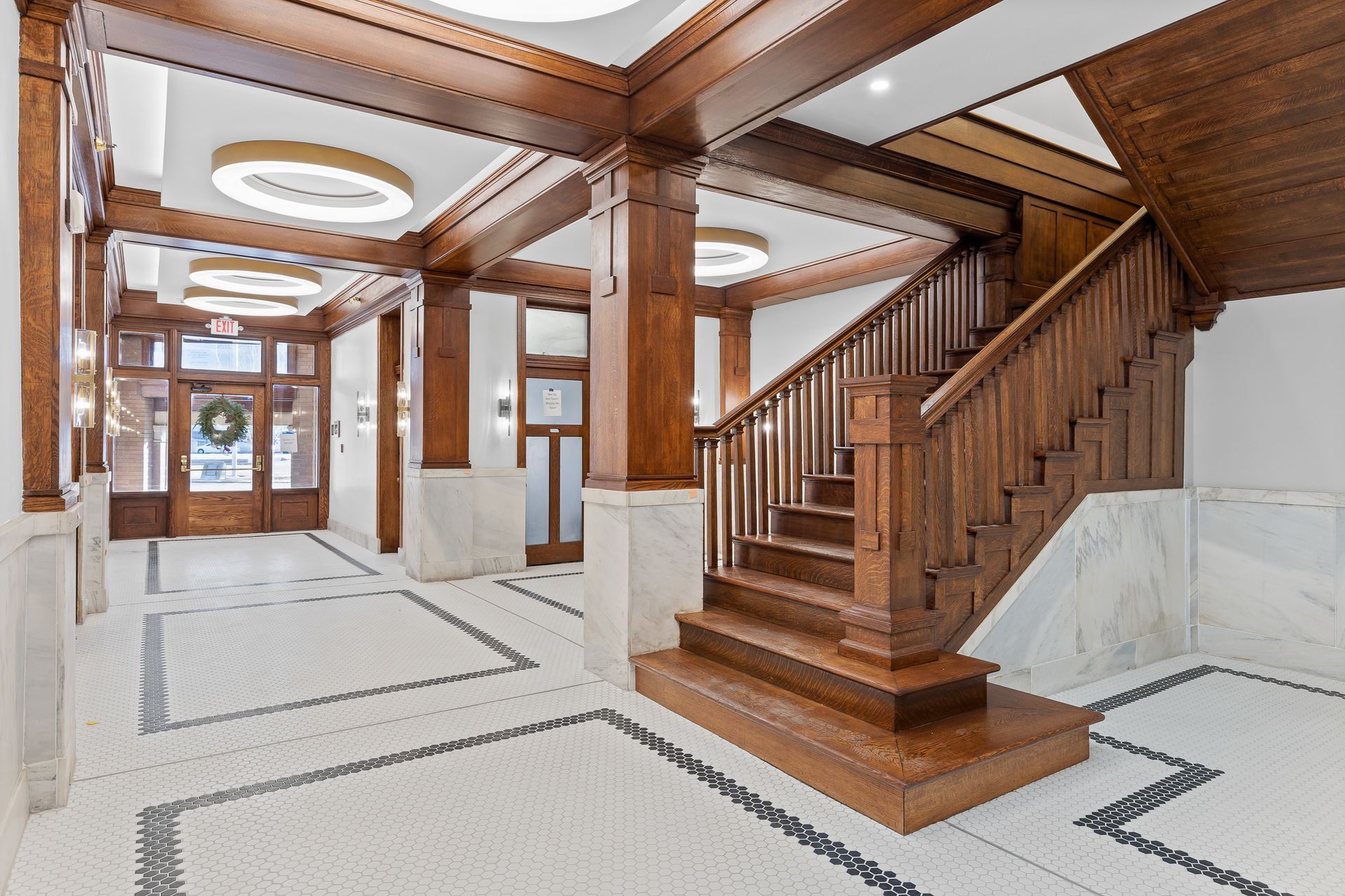 A wooden staircase in a building with a tiled floor