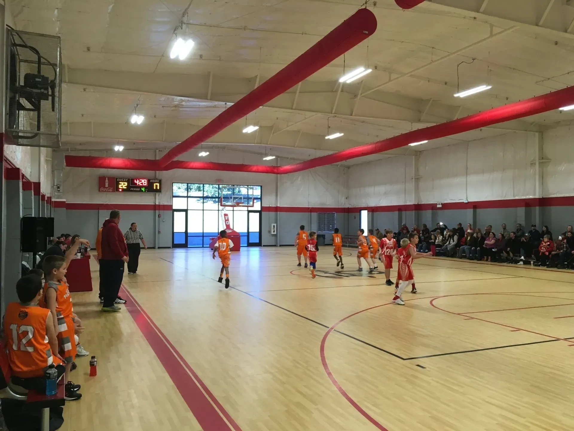 A group of children are playing basketball in a gym.