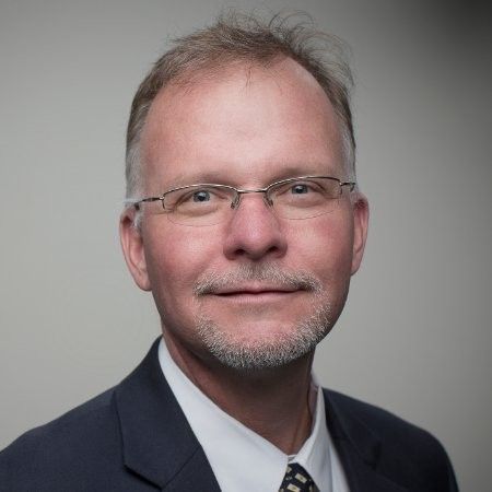 A man with glasses and a beard is wearing a suit and tie.