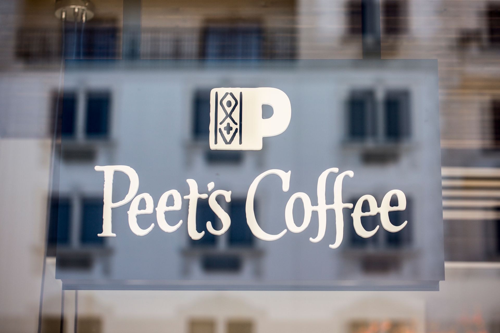 The logo for peet 's coffee is on the window of a building.