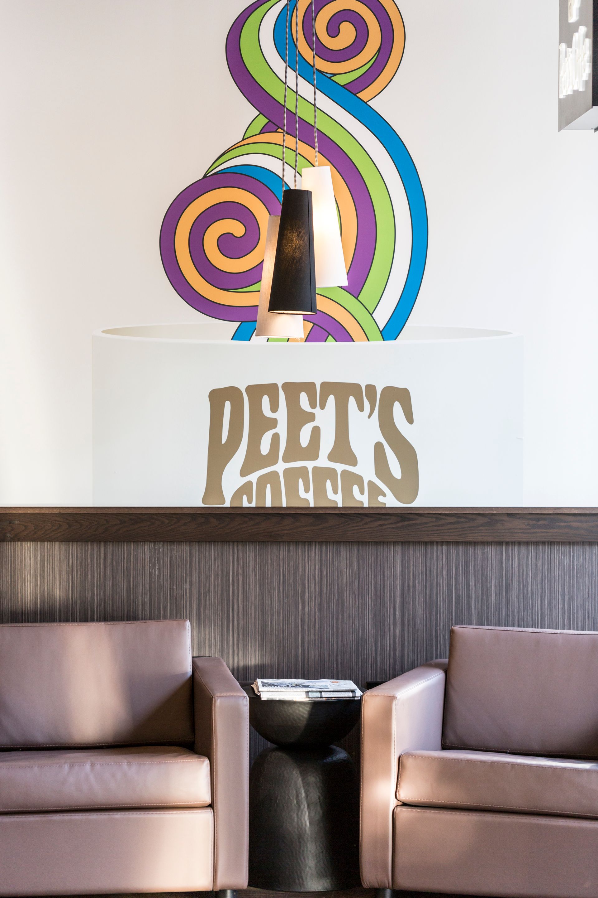 Two chairs and a couch in a room with a peet 's sign on the wall
