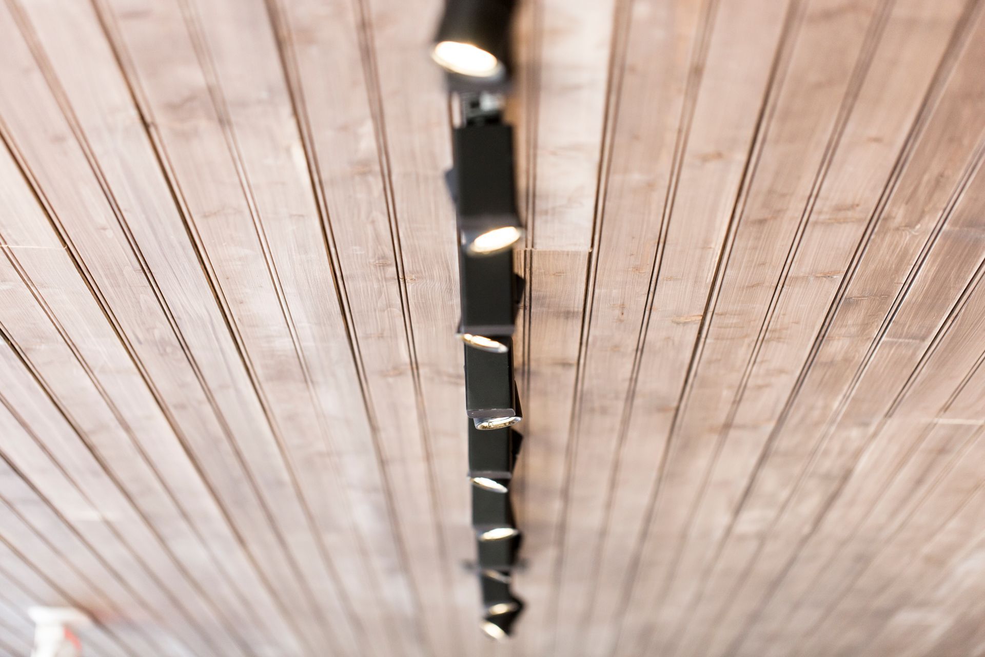 A wooden ceiling with a row of lights hanging from it