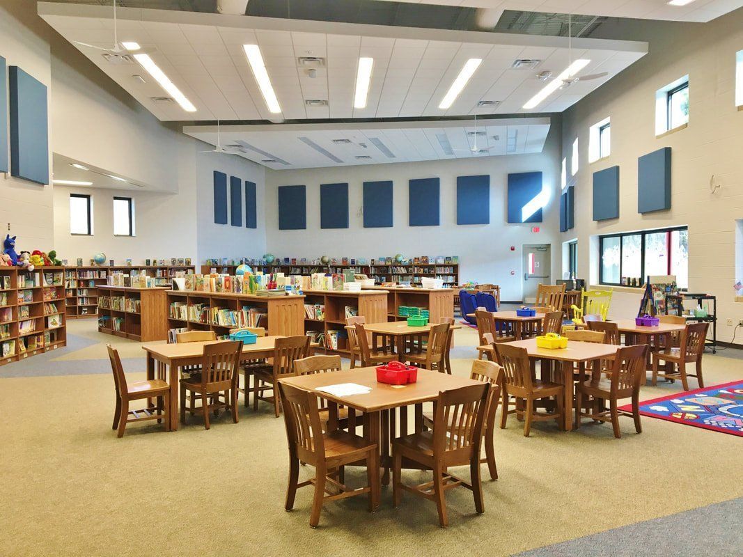 A large room with tables and chairs in a library