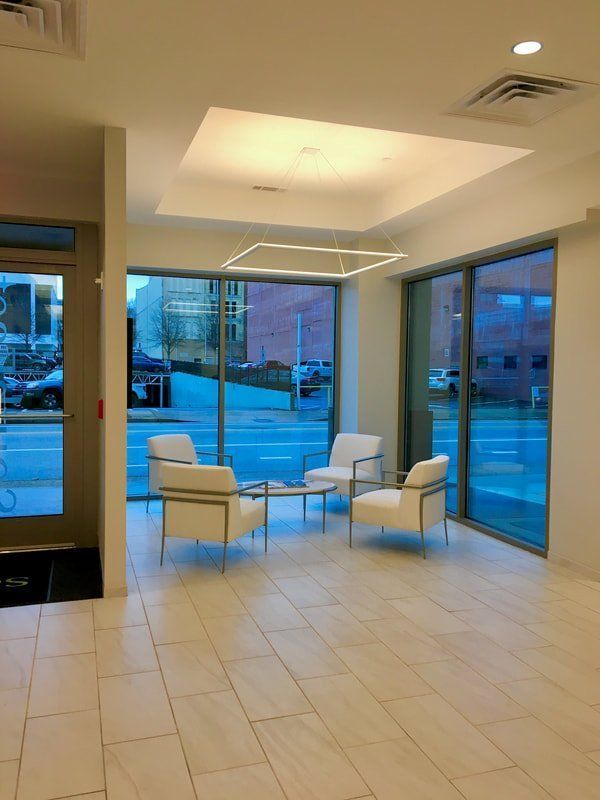 A waiting room with white chairs and a table