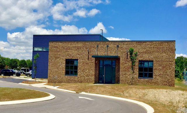 A brick building with a blue roof is sitting next to a road.