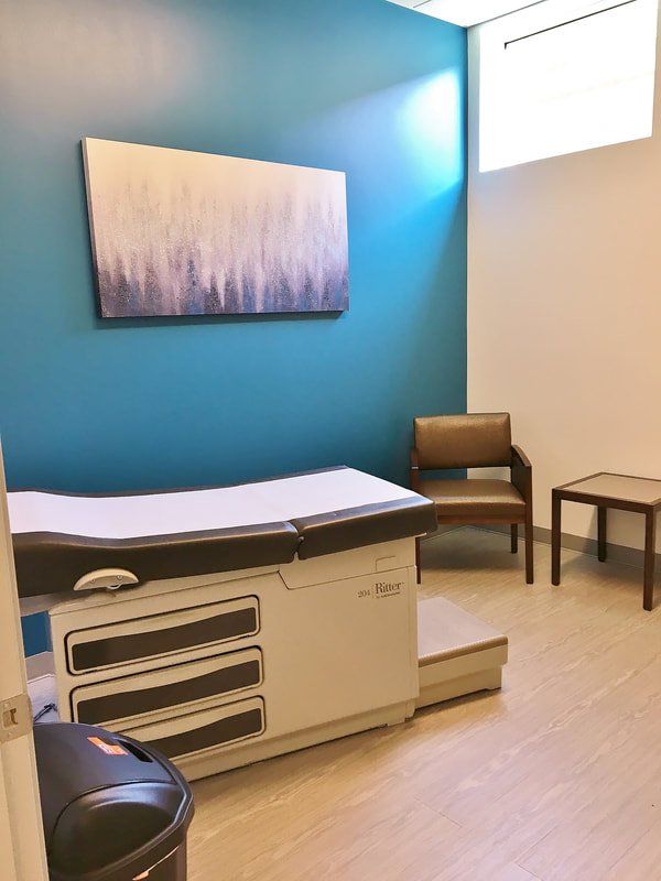 A doctor 's office with a table and chairs and a trash can