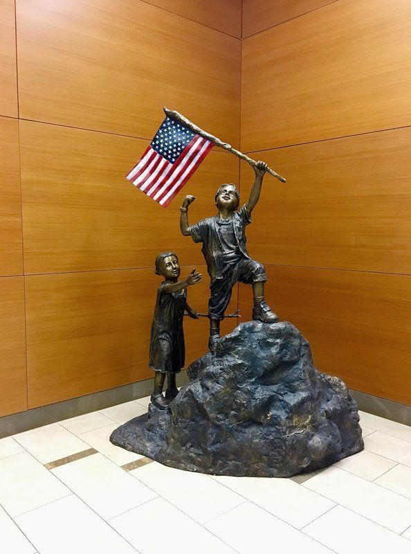 A statue of two children holding an american flag