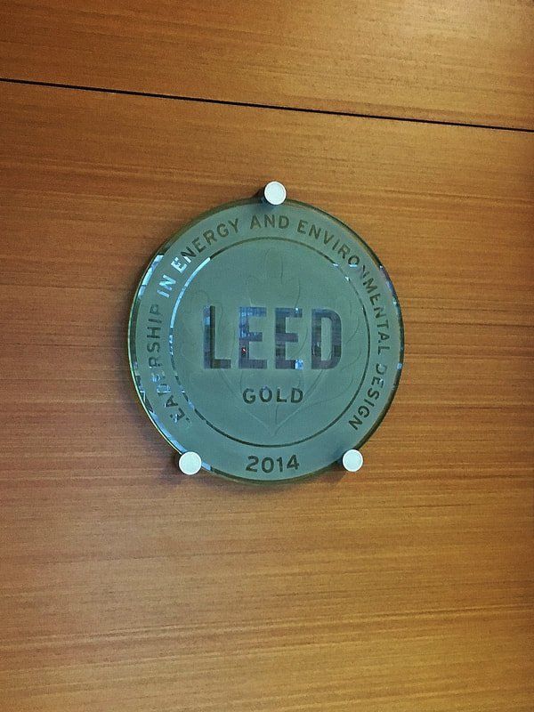 A leed gold plaque is hanging on a wooden wall