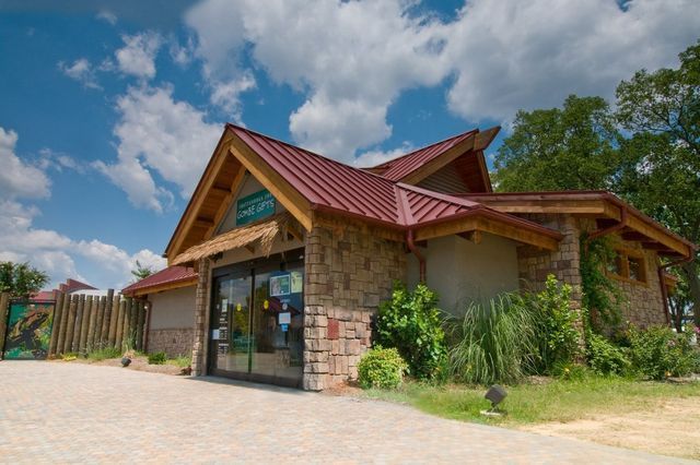 A large stone building with a red roof is surrounded by trees and grass.