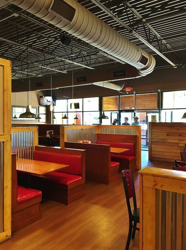 The inside of a restaurant with red booths and tables