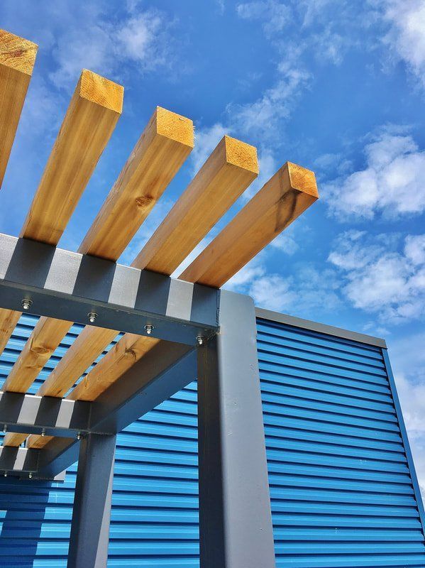 A blue building with a wooden pergola on top of it