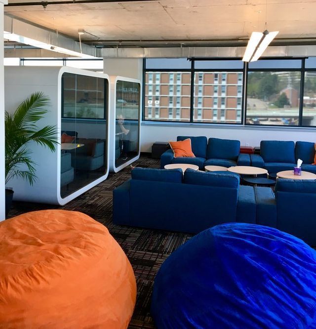 A living room with blue couches and orange bean bag chairs