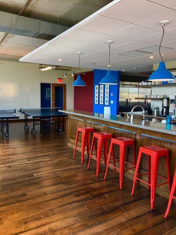 A kitchen with red stools and a ping pong table.