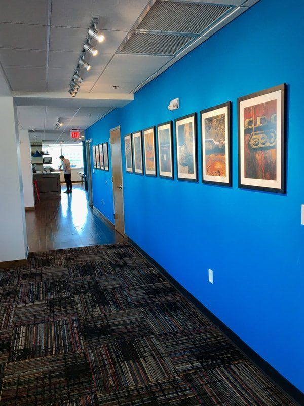 A hallway with blue walls and framed pictures on the wall.