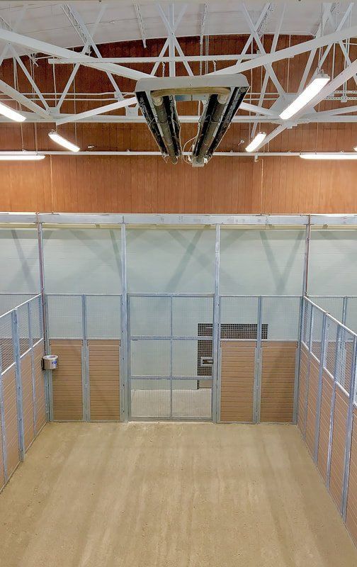 A large empty gym with a wooden floor and a ceiling fan.