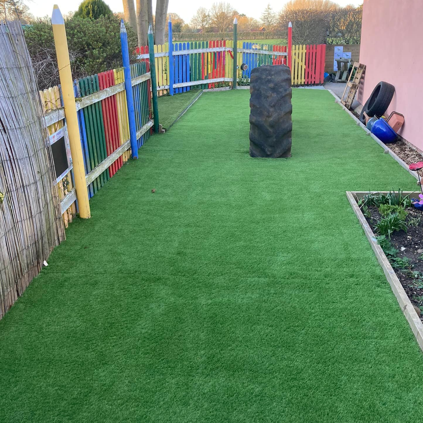 There is a tire on the artificial grass lawn. 