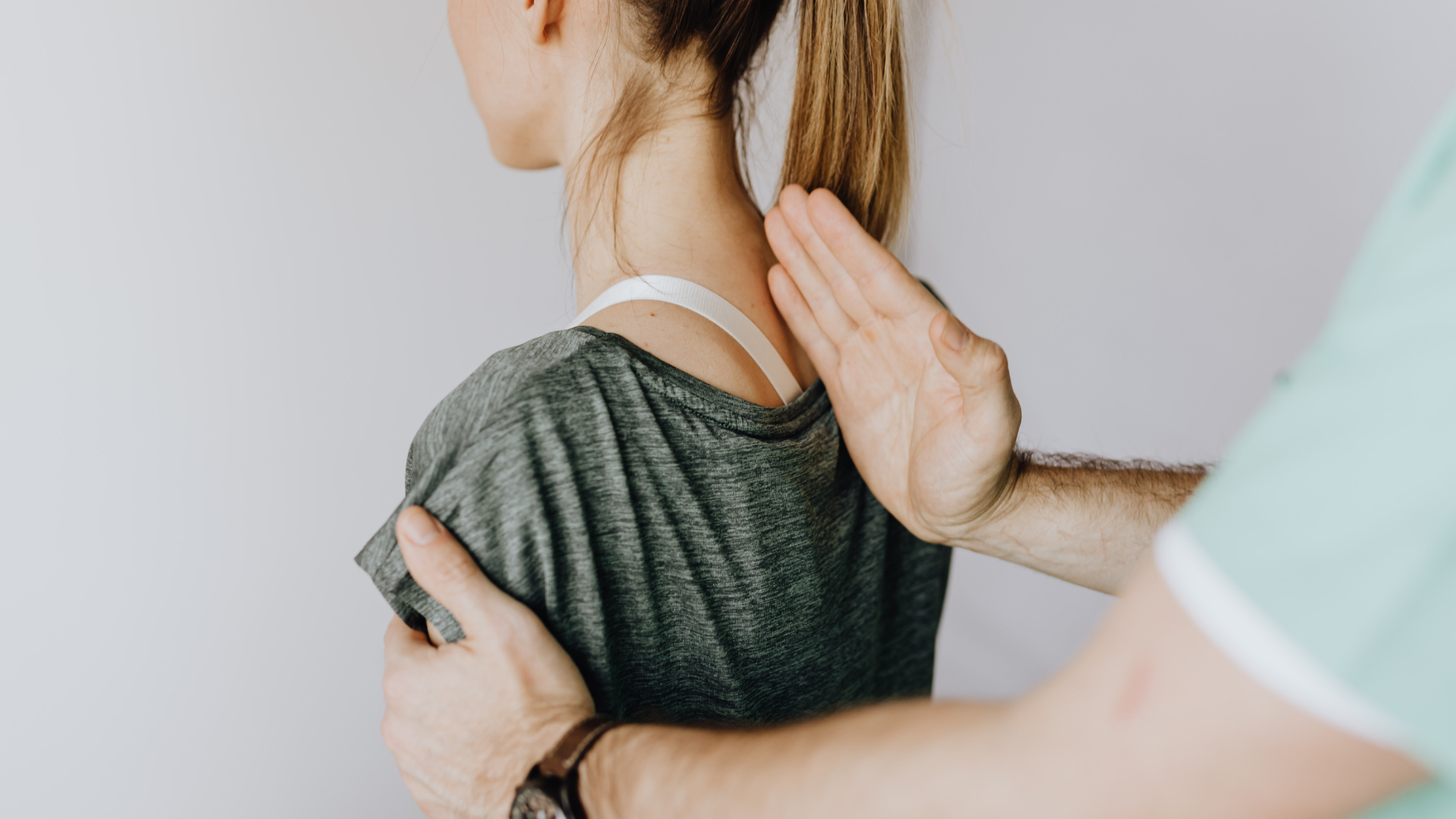 Person receiving physical therapy on their upper back; hands placed on shoulders and neck.