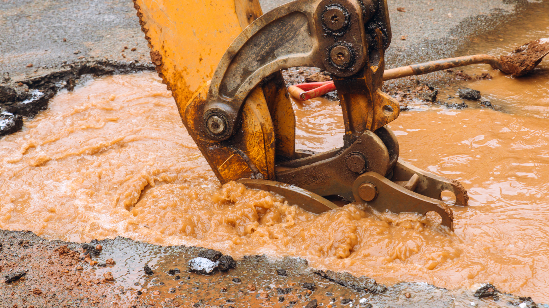 Excavator bucket scooping muddy water at a construction site