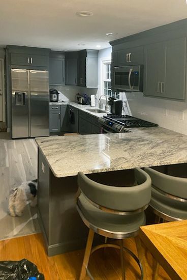 Gray kitchen with stainless steel appliances, granite countertops, and bar stools.