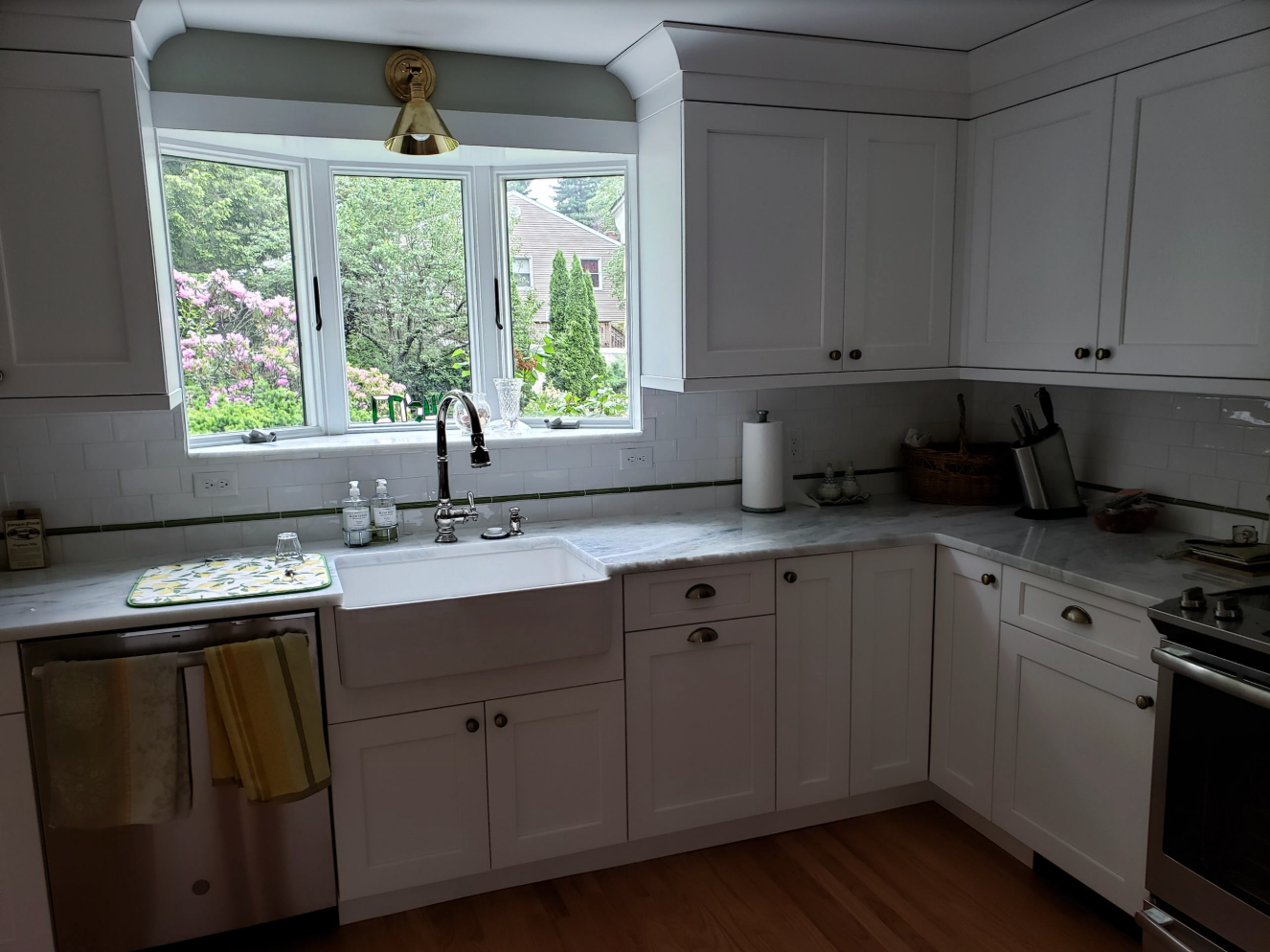 White kitchen with a window above a farmhouse sink, cabinets, and countertops.