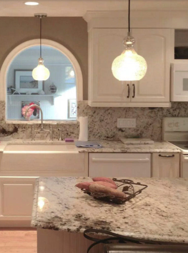 Kitchen with white cabinets, granite countertops, and two pendant lights.