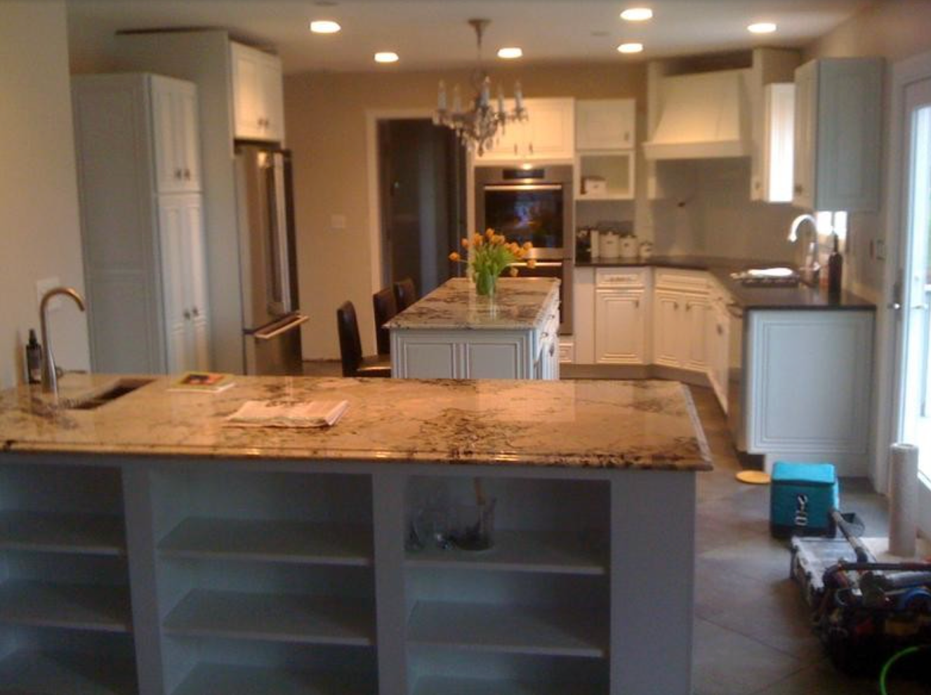 Spacious white kitchen with granite countertops, two islands, and stainless steel appliances.