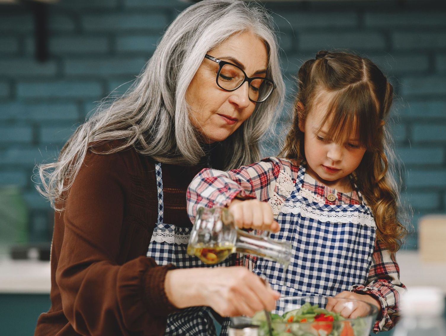 Child and older adult cooking together.