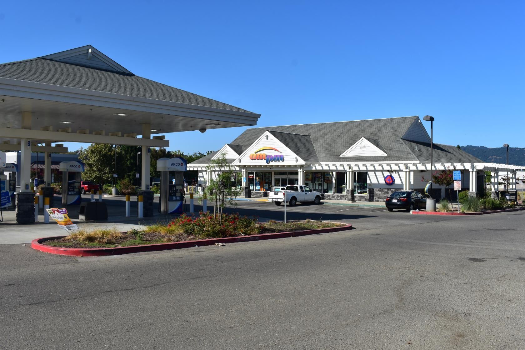 Gas station with a convenience store under a clear blue sky.