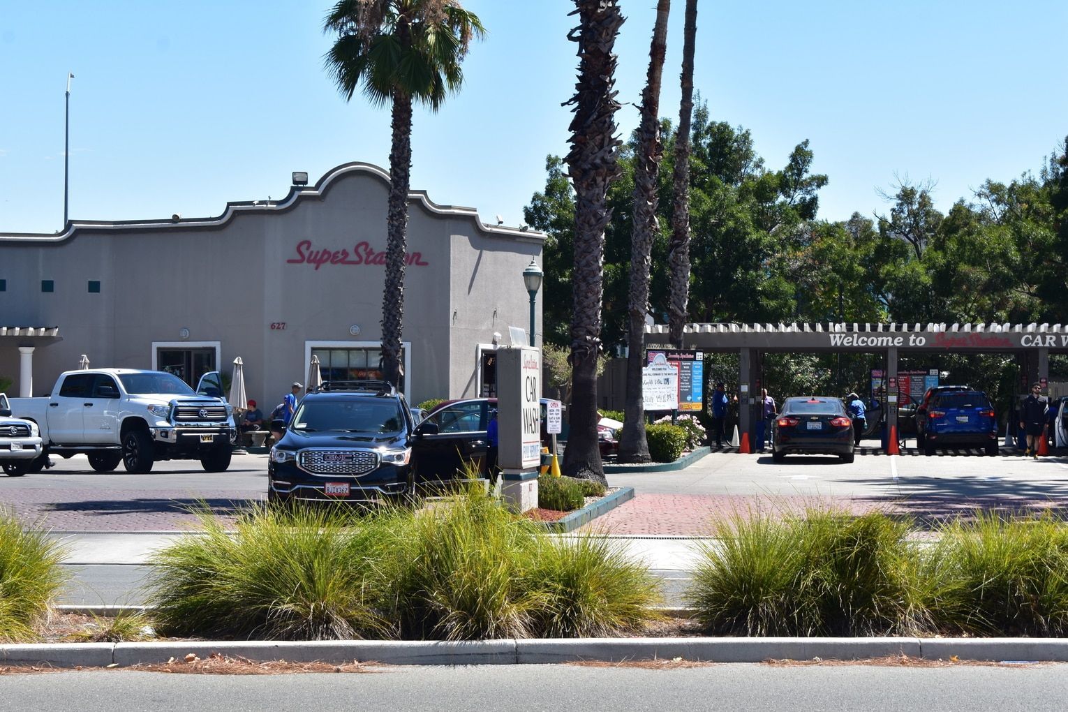 Super Star gas station with cars, palm trees, and blue sky.