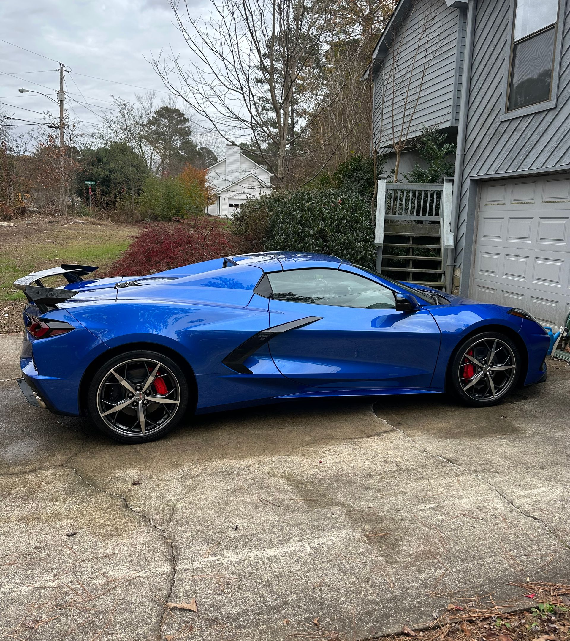 Blue sports car parked on a concrete driveway next to a garage.