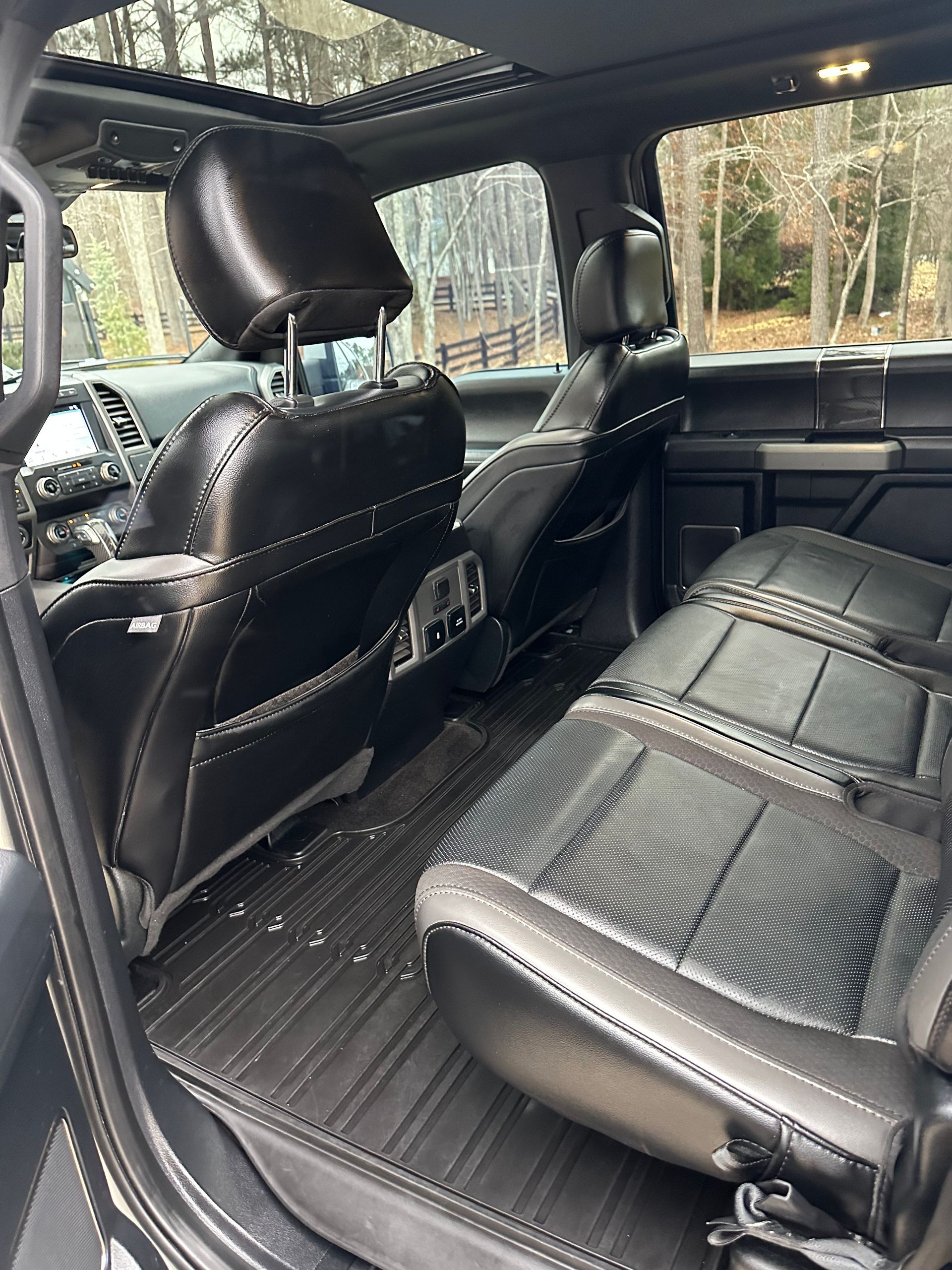 Black leather interior of a truck, featuring rear seats and headrests.
