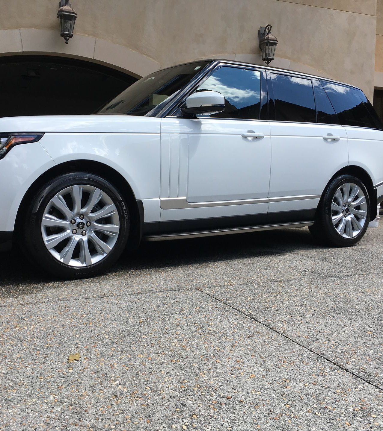 White Range Rover SUV parked on a gravel driveway, in front of a building.