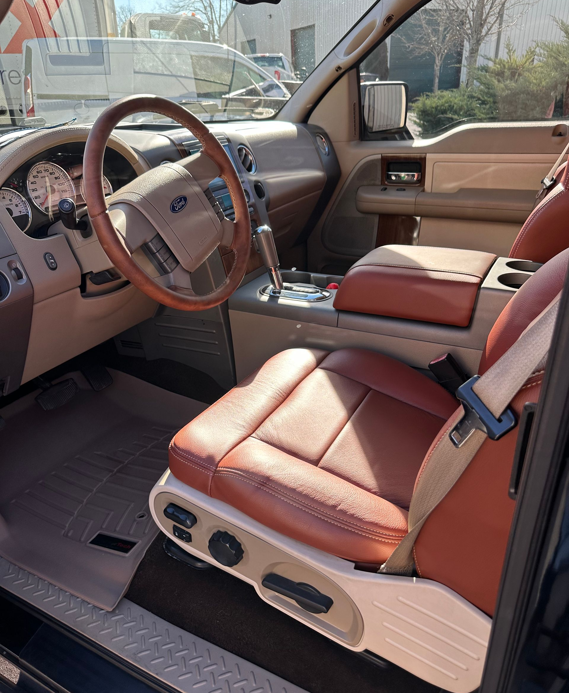 Interior of a tan and brown Ford pickup truck, showing the front seat, dashboard, and steering wheel.